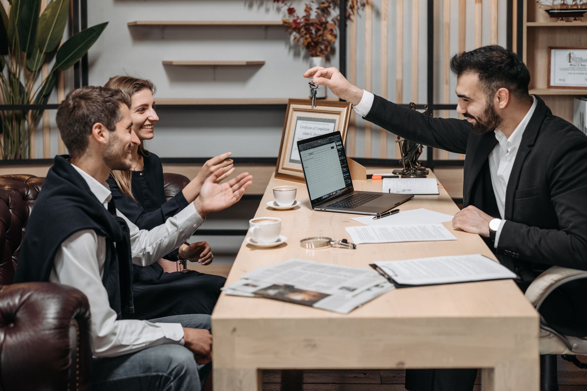 Professionnel d'affaires remettant des clés à des clients souriants à un bureau lors d'une consultation.