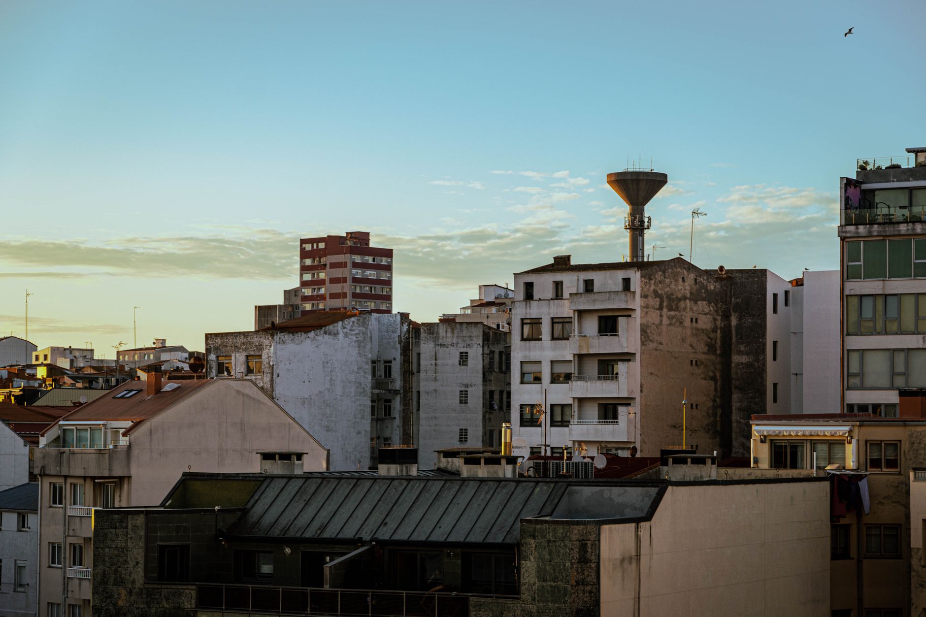 Vue panoramique de bâtiments résidentiels au coucher du soleil à A Coruña, Espagne, avec la silhouette d'un château d'eau.