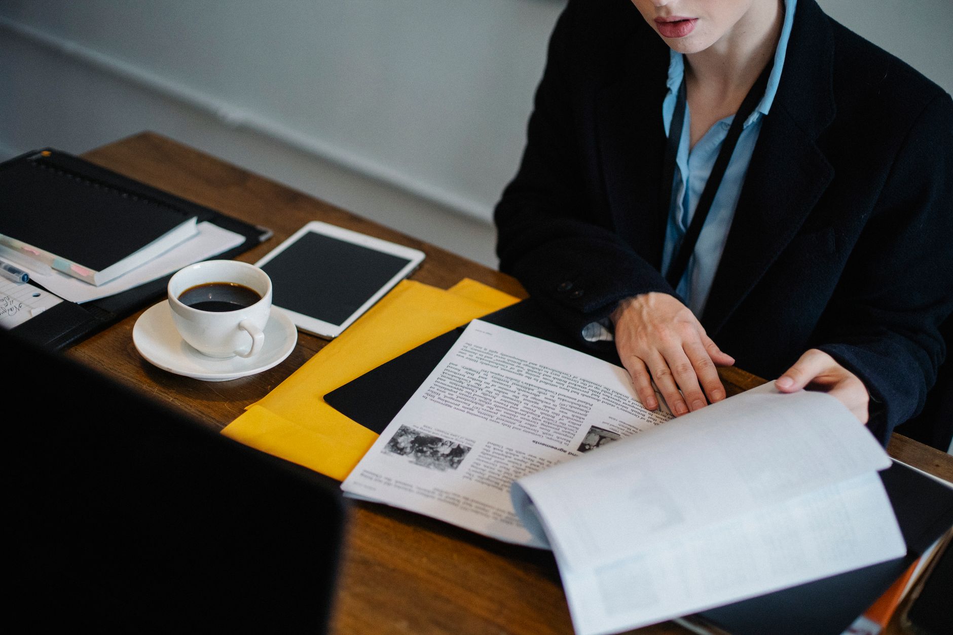 Vue aérienne d'une femme d'affaires anonyme en tenue formelle assise à une table avec une tablette et du café chaud et consultant des documents