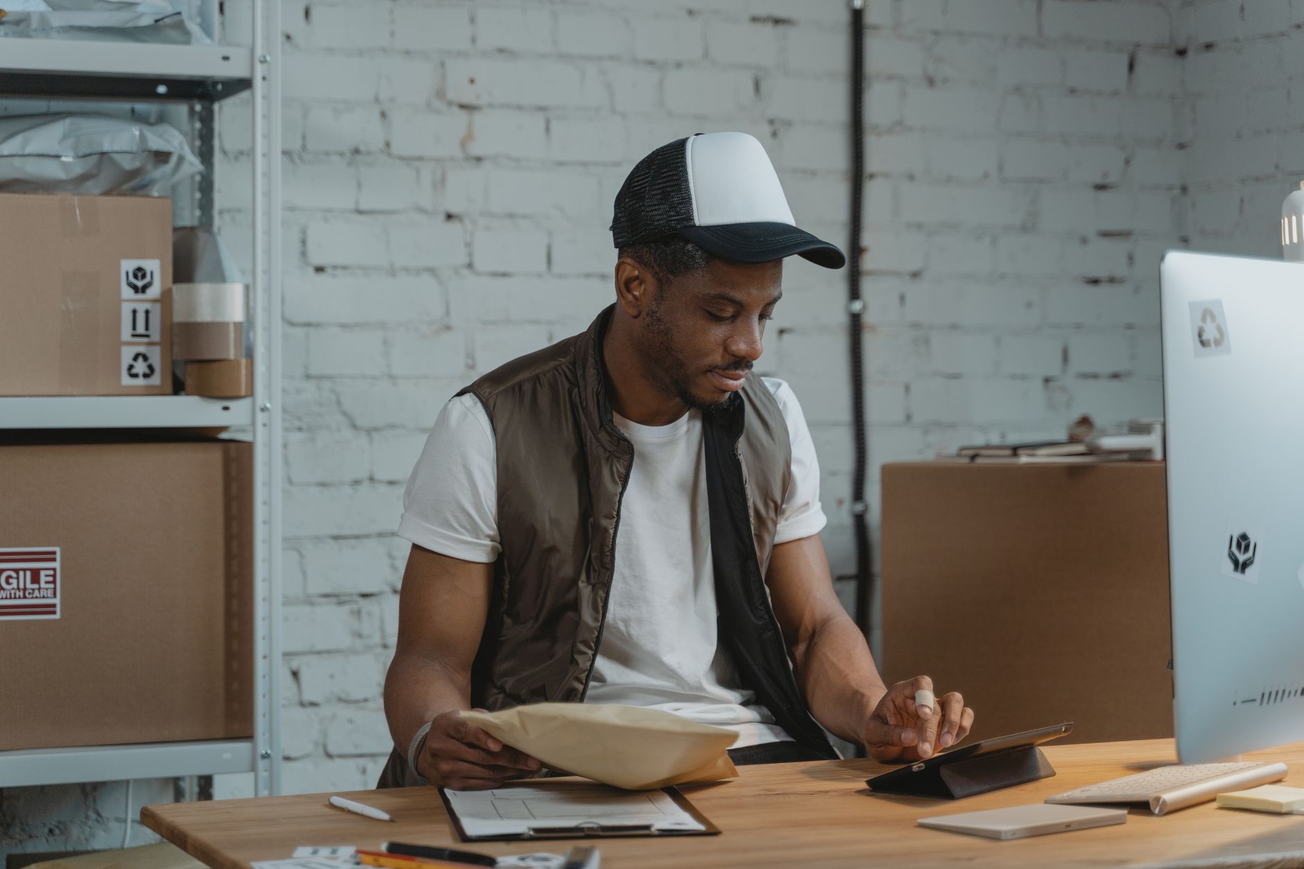 Un homme dans un entrepôt gère des commandes d'e-commerce et utilise une tablette pour la logistique.